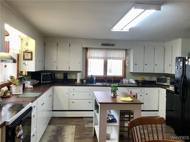 kitchen featuring electric stove, stainless steel microwave, black fridge, white cabinetry, and a sink