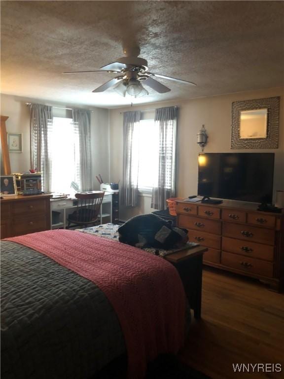 bedroom with ceiling fan, a textured ceiling, and dark hardwood / wood-style flooring