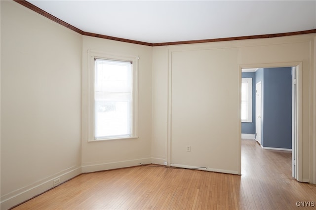 spare room with ornamental molding and light hardwood / wood-style flooring