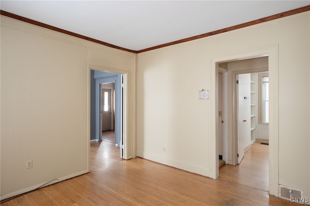 empty room with crown molding and light hardwood / wood-style floors