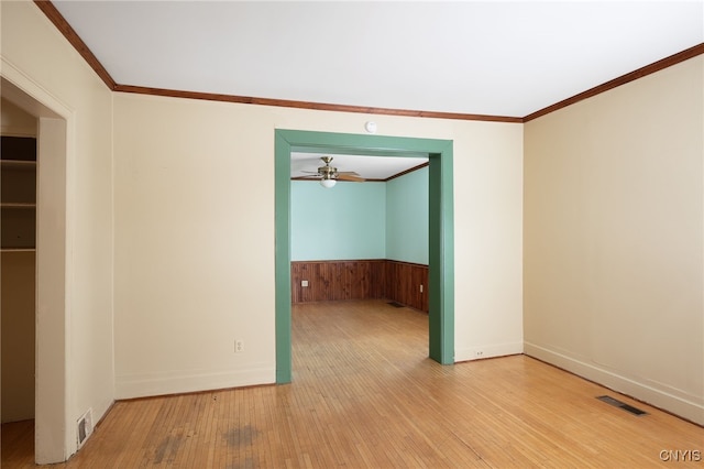 spare room featuring ceiling fan, ornamental molding, wooden walls, and hardwood / wood-style floors