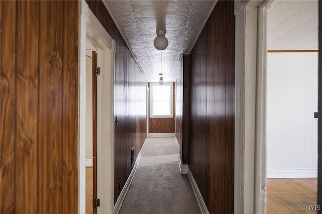 hallway featuring carpet floors and wooden walls