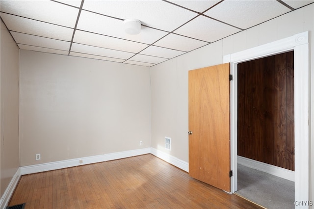 empty room with hardwood / wood-style flooring and a drop ceiling