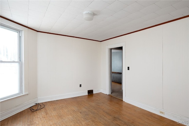 empty room with hardwood / wood-style floors and crown molding