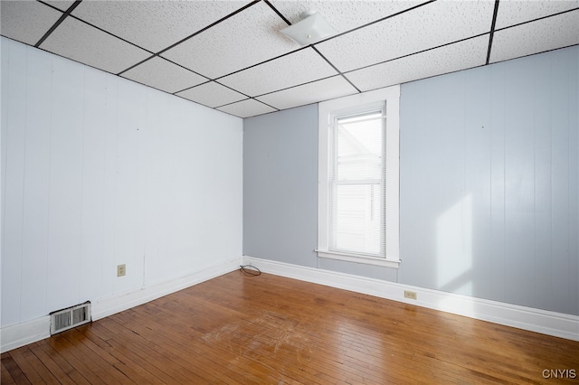 unfurnished room with hardwood / wood-style flooring and a drop ceiling