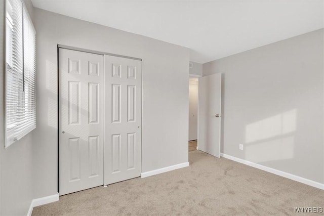 unfurnished bedroom with light carpet and a closet