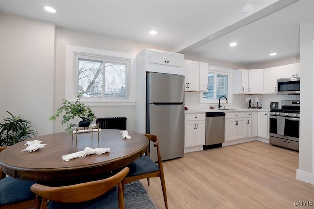 kitchen featuring appliances with stainless steel finishes, sink, white cabinets, and light hardwood / wood-style flooring