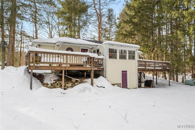 snow covered back of property featuring a deck