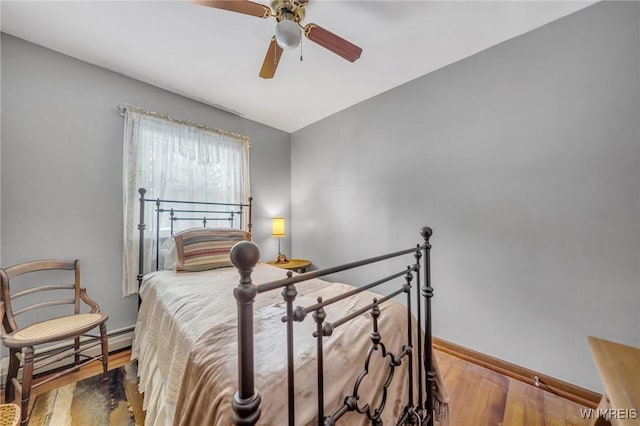 bedroom with ceiling fan, wood-type flooring, and a baseboard radiator