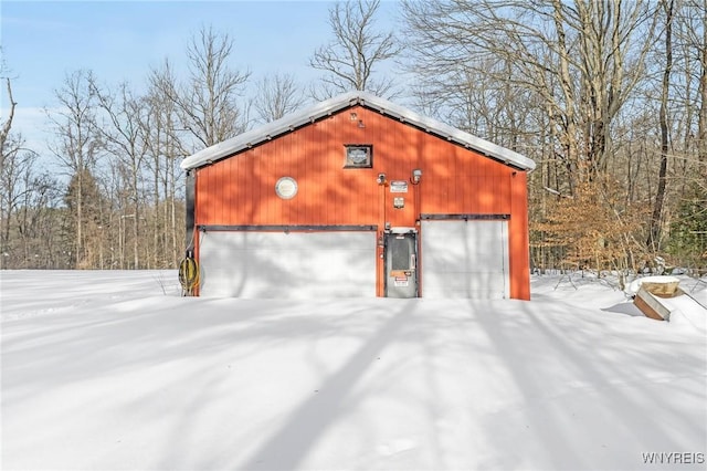 snow covered structure featuring a garage