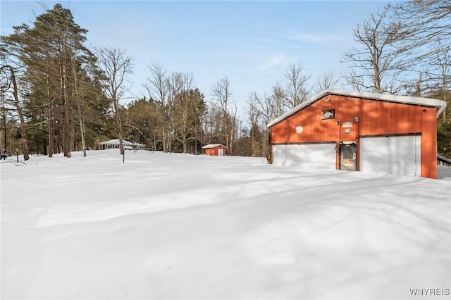 yard covered in snow featuring a garage and an outdoor structure