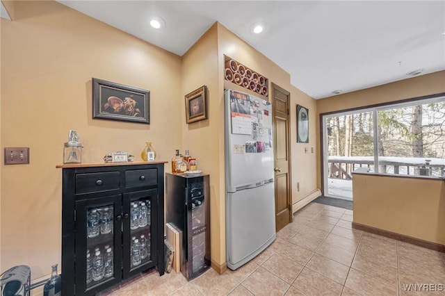 kitchen with a baseboard heating unit, light tile patterned floors, and stainless steel fridge