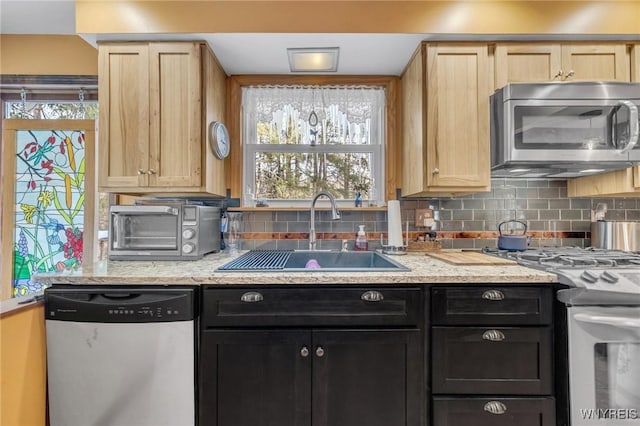 kitchen with tasteful backsplash, appliances with stainless steel finishes, sink, and light brown cabinets