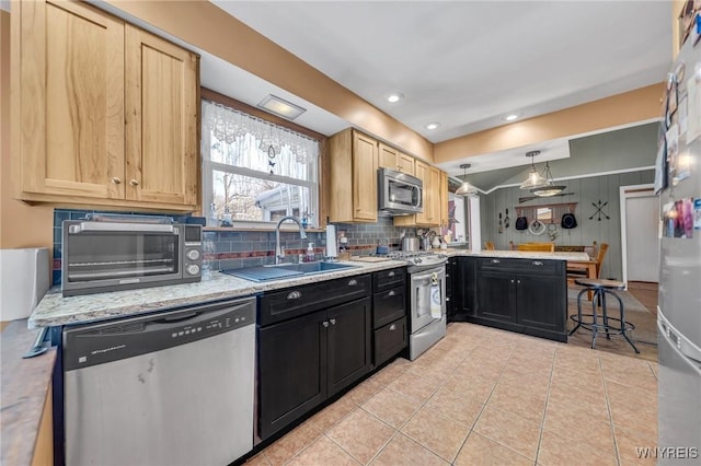 kitchen with appliances with stainless steel finishes, decorative light fixtures, kitchen peninsula, and sink