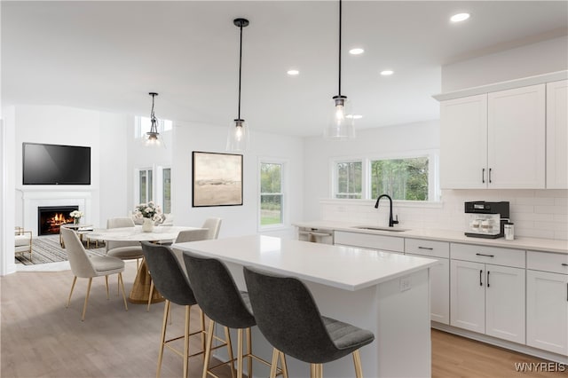 kitchen featuring hanging light fixtures, a kitchen island, sink, and white cabinets