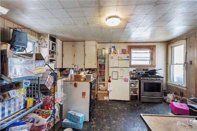 kitchen with wooden walls, gas stove, and white refrigerator