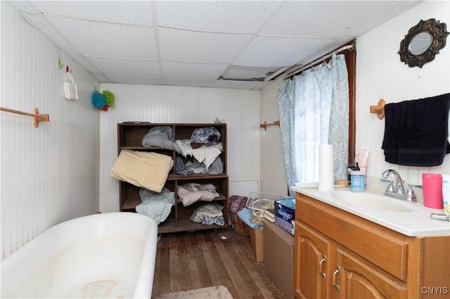 bathroom featuring wood-type flooring, a bath, vanity, and a drop ceiling