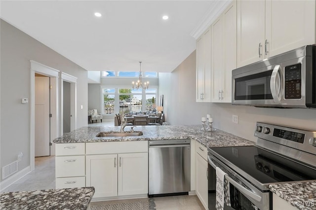 kitchen featuring white cabinetry, sink, kitchen peninsula, stainless steel appliances, and light stone countertops