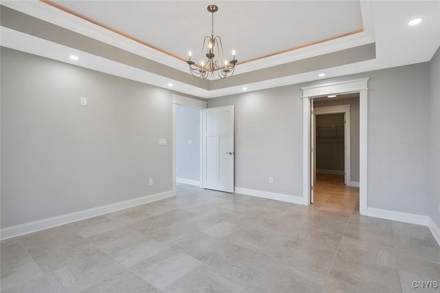 empty room featuring a raised ceiling, ornamental molding, and a chandelier