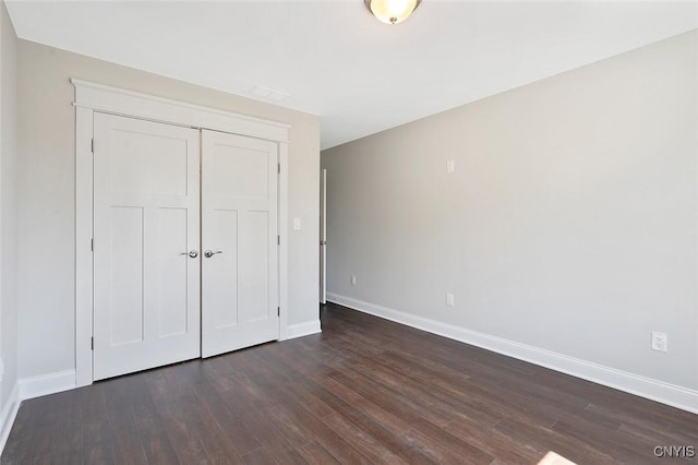 unfurnished bedroom with dark hardwood / wood-style flooring and a closet