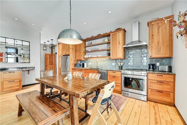 kitchen with open shelves, a sink, decorative backsplash, appliances with stainless steel finishes, and wall chimney exhaust hood