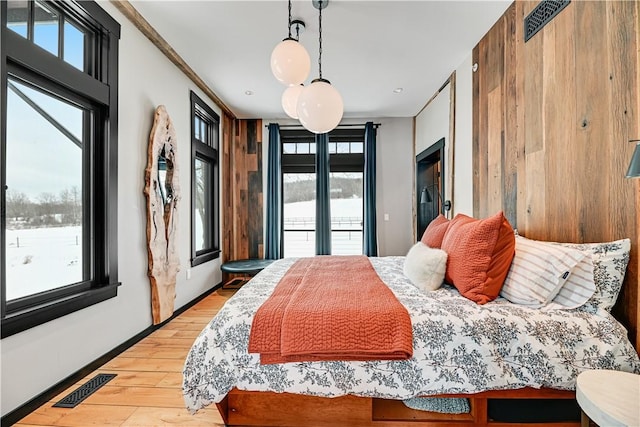 bedroom with visible vents, baseboards, wood finished floors, and access to outside