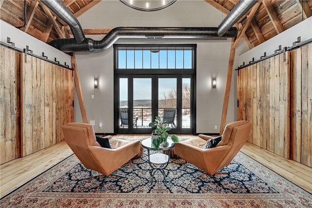 sitting room featuring wood ceiling, high vaulted ceiling, a barn door, and wood-type flooring