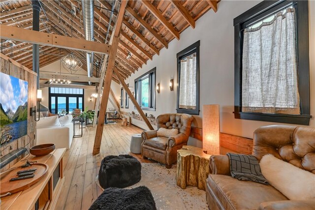 living room with a chandelier, beamed ceiling, a wealth of natural light, and wood-type flooring