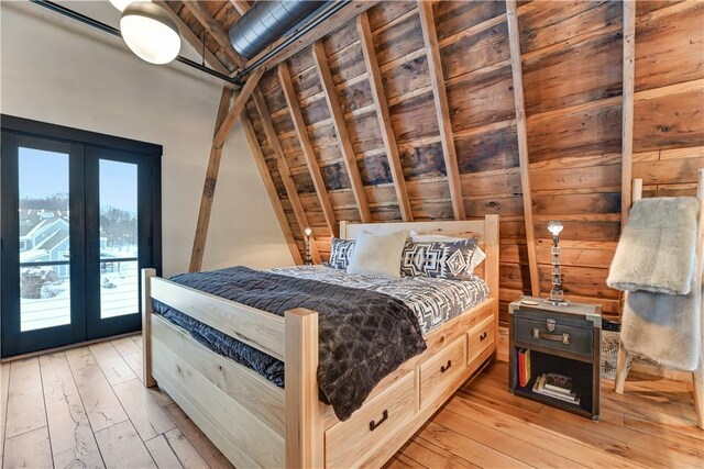 bedroom with lofted ceiling, access to outside, light wood-style floors, and french doors