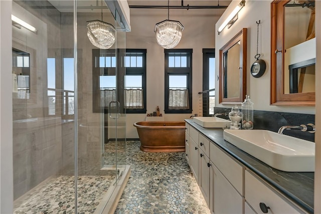 full bath featuring a freestanding bath, a stall shower, a chandelier, and a sink