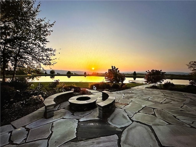 patio terrace at dusk with a water view and an outdoor fire pit