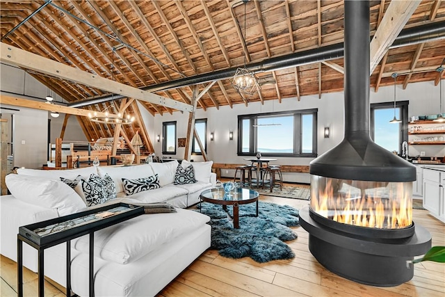 living area with a wood stove, hardwood / wood-style flooring, wood ceiling, a chandelier, and vaulted ceiling with beams