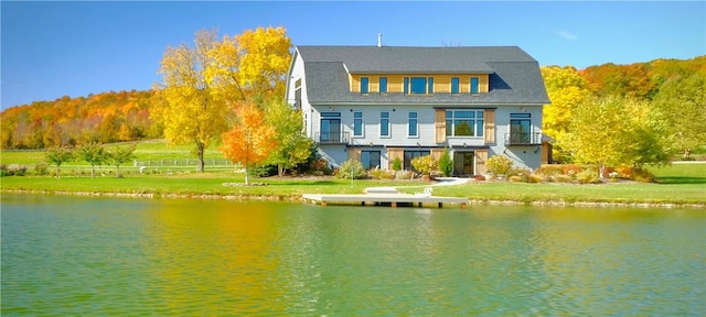 back of house with a water view and a lawn