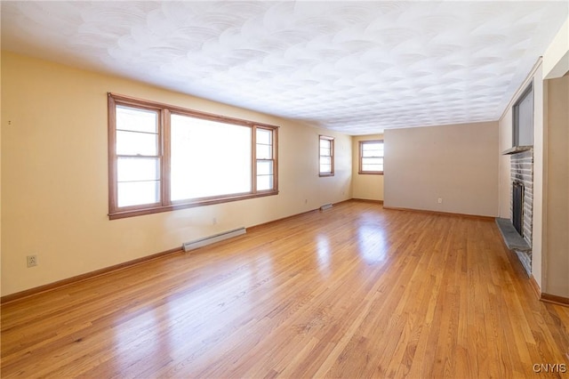 unfurnished living room with a baseboard radiator, a fireplace, light hardwood / wood-style flooring, and a textured ceiling