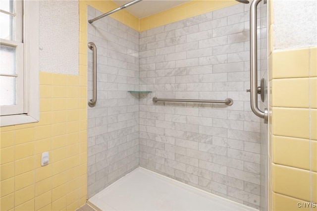 bathroom with tiled shower and tile walls