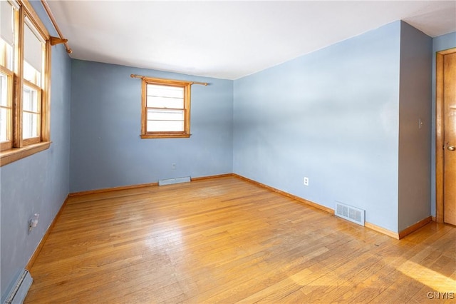 spare room featuring a baseboard heating unit and light hardwood / wood-style floors