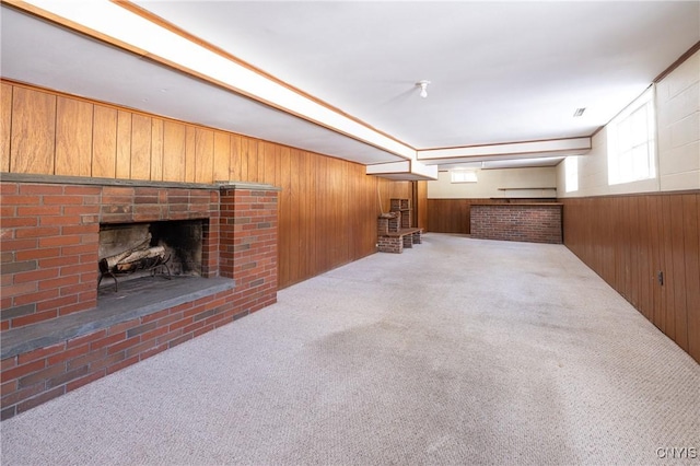 basement with a fireplace, wooden walls, and light carpet