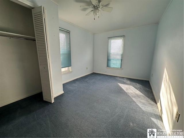 unfurnished bedroom with crown molding, ceiling fan, dark carpet, and a closet