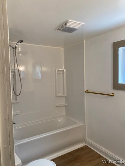 bathroom featuring tub / shower combination, hardwood / wood-style floors, and toilet