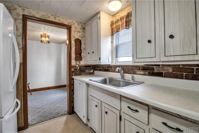 kitchen with pendant lighting, sink, light carpet, and white appliances