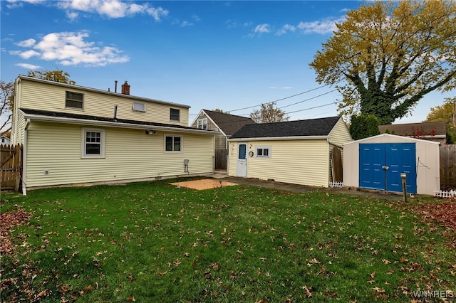 rear view of property featuring a lawn and a storage unit