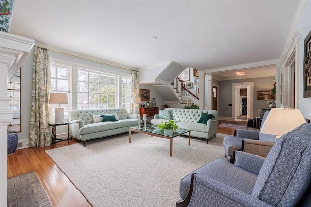 living room with light hardwood / wood-style flooring, ornamental molding, and ornate columns