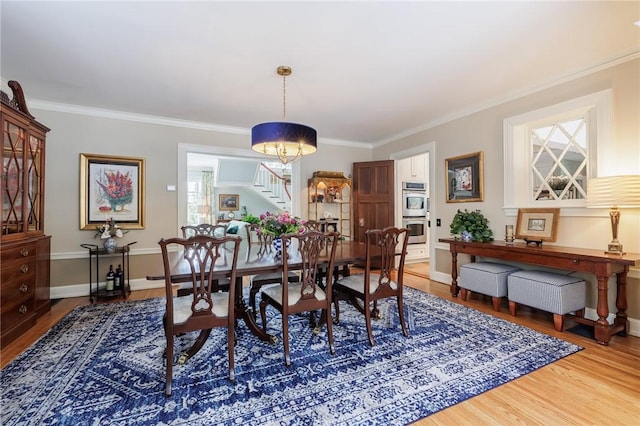 dining space featuring hardwood / wood-style flooring, ornamental molding, and a chandelier