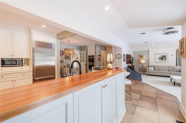 kitchen with appliances with stainless steel finishes, butcher block countertops, decorative light fixtures, sink, and white cabinets