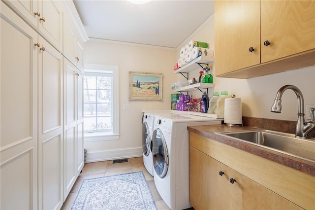 laundry area featuring sink, crown molding, cabinets, light tile patterned floors, and washing machine and dryer