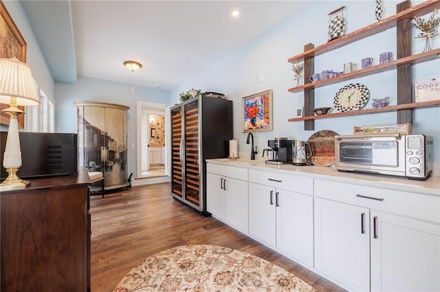 kitchen featuring sink, dark wood-type flooring, white cabinetry, black fridge, and beverage cooler