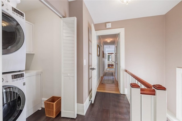 laundry room with cabinets, stacked washing maching and dryer, and dark hardwood / wood-style floors