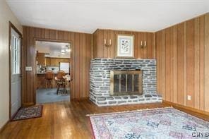 unfurnished living room featuring wooden walls and dark hardwood / wood-style floors