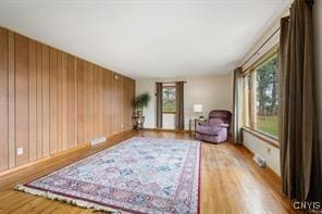 living area with hardwood / wood-style floors and wooden walls