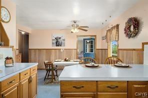 kitchen featuring ceiling fan, a kitchen bar, a kitchen island, and wood walls